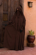 Jilbab 2 pièces marron chocolat en crêpe royal avec khimar long, robe ample et manches resserrées, présenté de face.