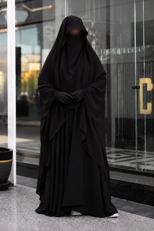 Jilbab 2 pièces noir en crêpe royal porté de face avec les mains jointes, offrant une couvrance complète, une coupe ample et un tombé élégant.