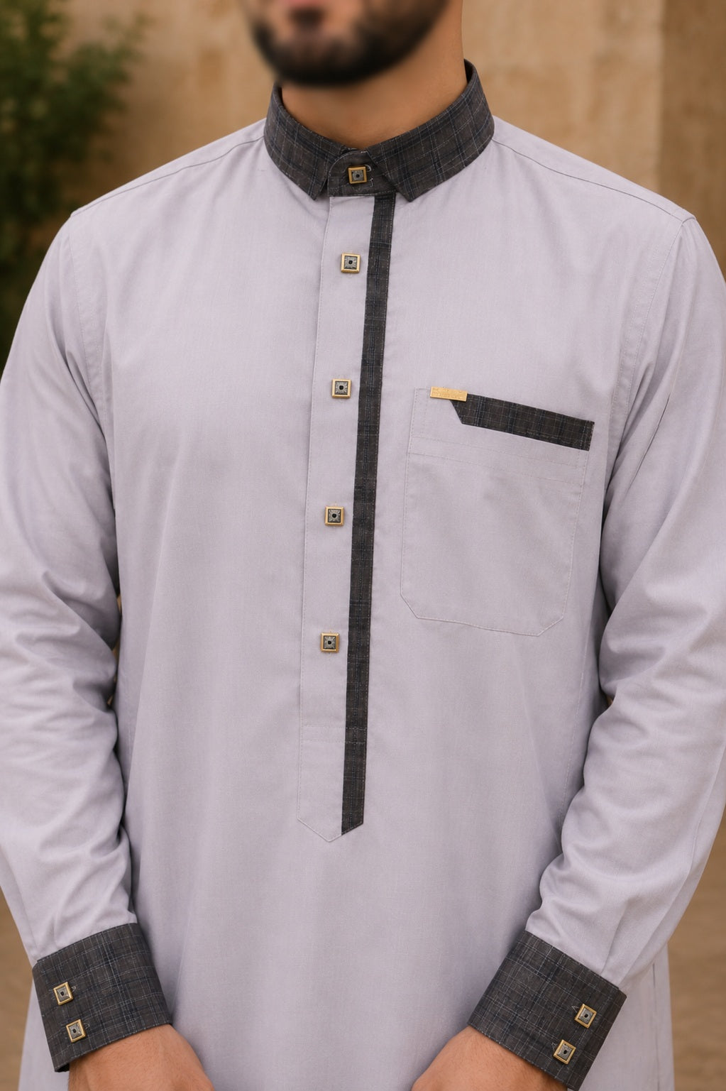 Qamis homme gris clair en coton premium avec col officier gris anthracite, cinq boutons décoratifs, poche poitrine et finitions élégantes.