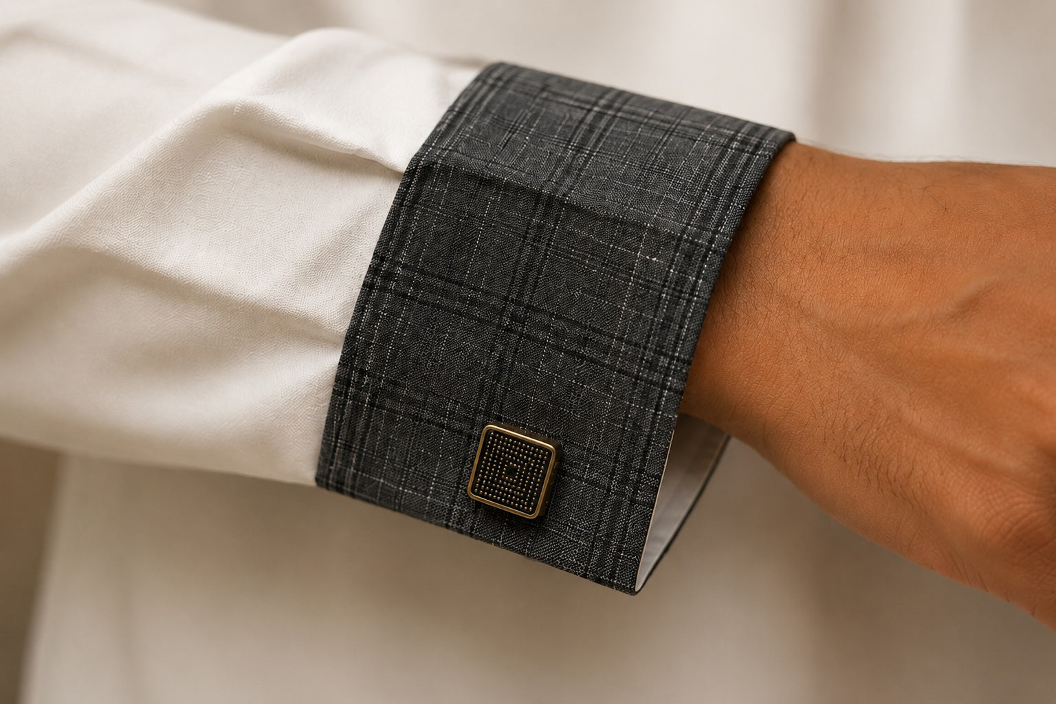 Détail du poignet d'un qamis blanc contemporain pour homme avec manche contrastée gris anthracite et bouton carré premium.