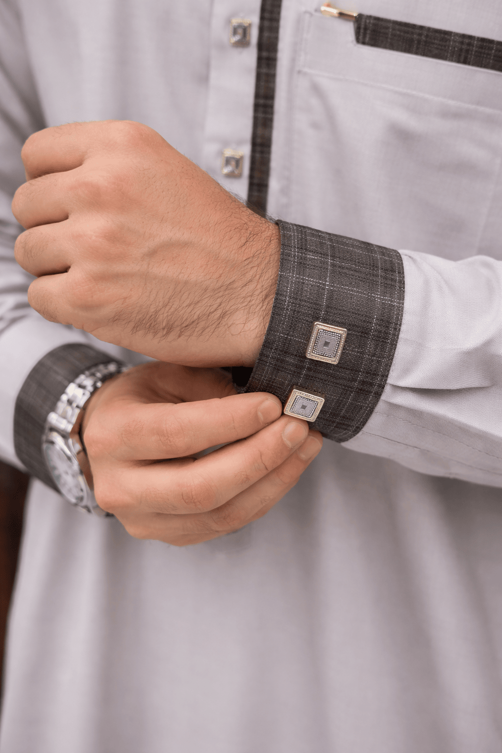 Gros plan sur les poignets d'un qamis gris clair premium avec manchettes gris anthracite et doubles boutons décoratifs au style contemporain.