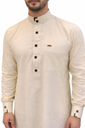Qamis saoudien homme vanille en coton premium avec col officier, coupe élégante et boutons décoratifs noirs et dorés raffinés.
